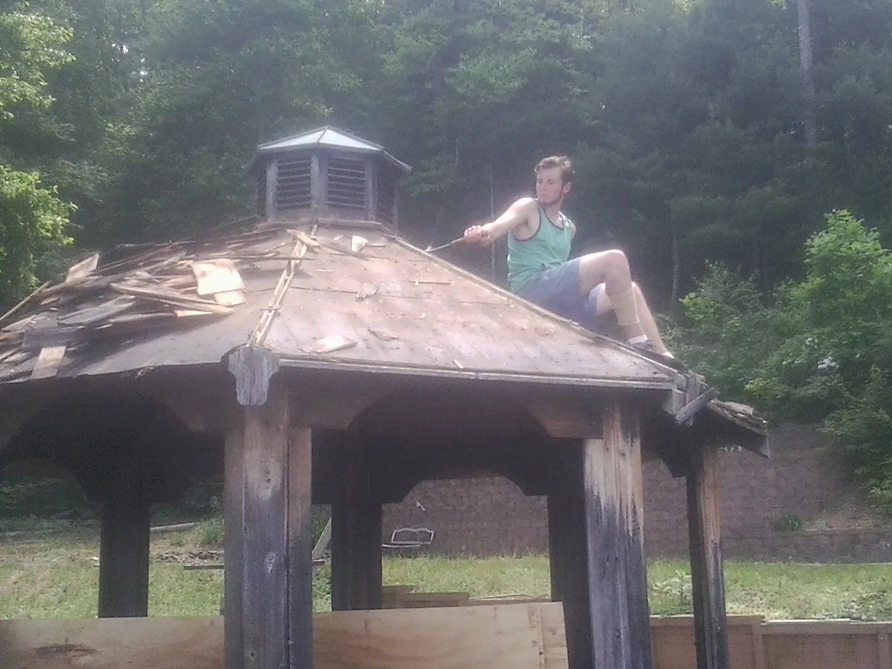Tearing the old roof off a wooden gazebo before new shakes in New Madison
