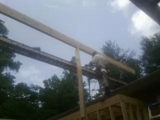 Carpenter setting a ridge beam over a new addition frame — Ice Dam Removal by Roofing Brothers in New Madison