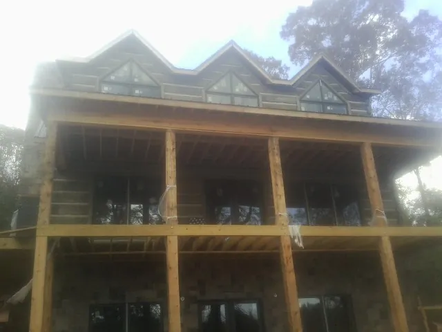 Dormers and porch framing on a large log home under construction — Roof Coating work by our crew in New Madison
