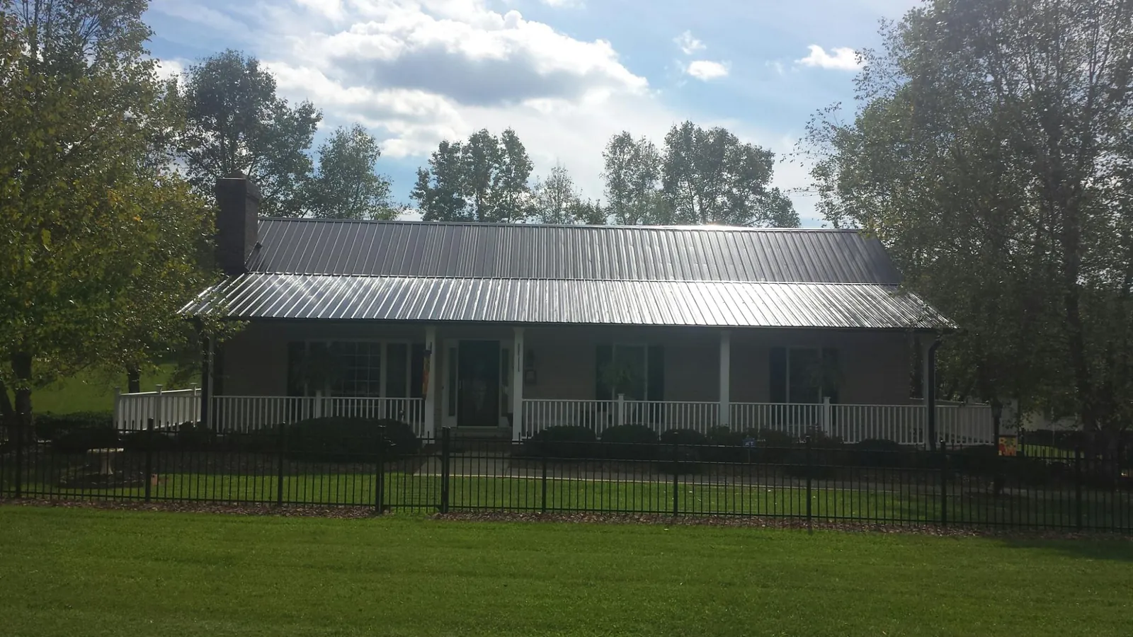 Gray metal roof on a brick ranch with a full width front porch — Gutter Guard Installation work by our crew in New Madison