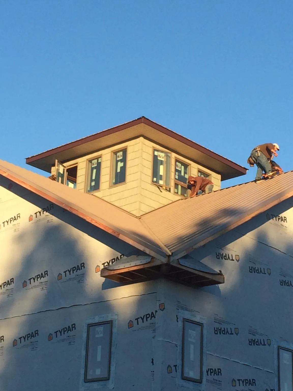 Roofers working around a rooftop cupola on a new metal roof at sunset — Roof Waterproofing in New Madison by Roofing Brothers